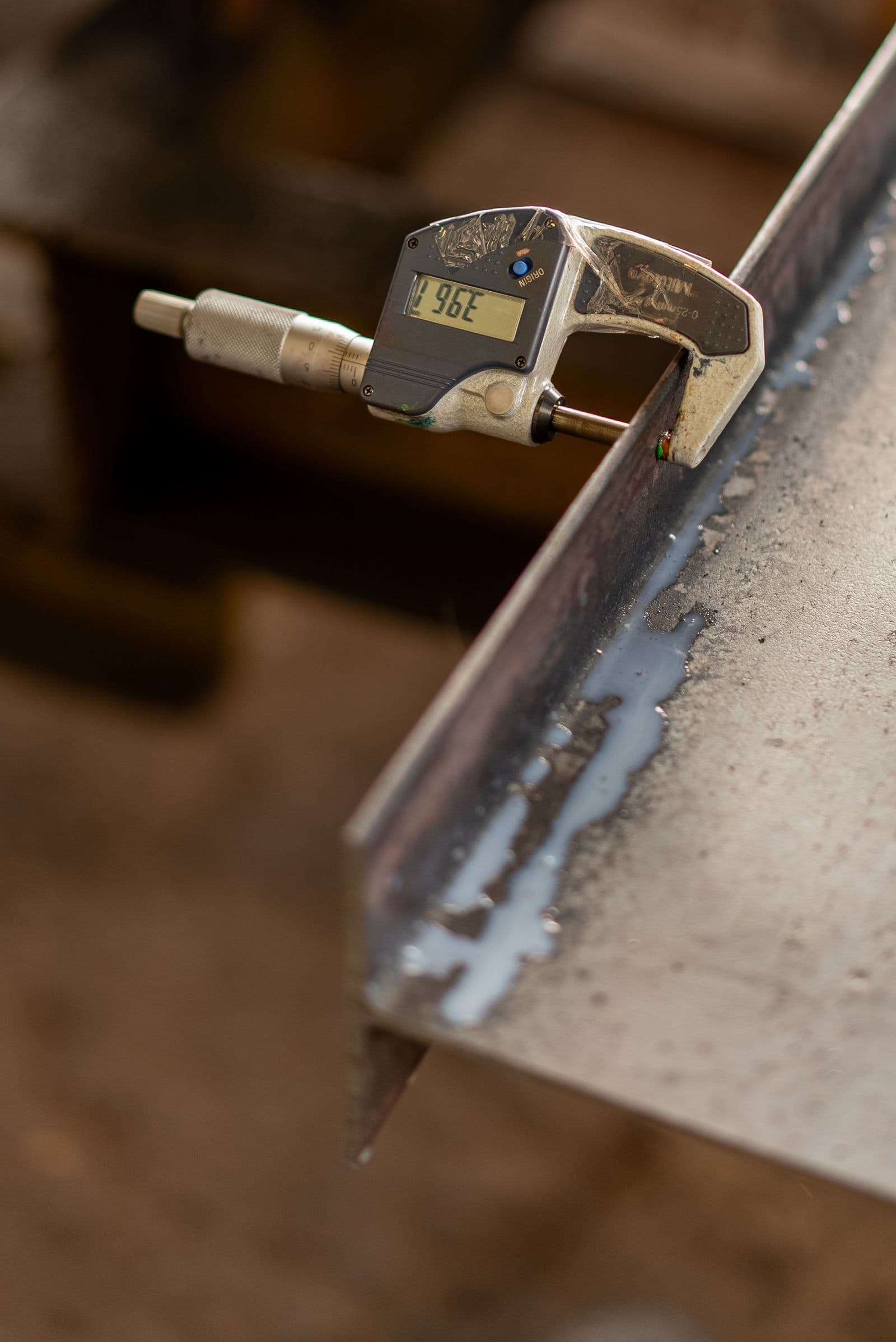 Quality inspector measuring a metal part with a digital micrometer — dimensional quality control